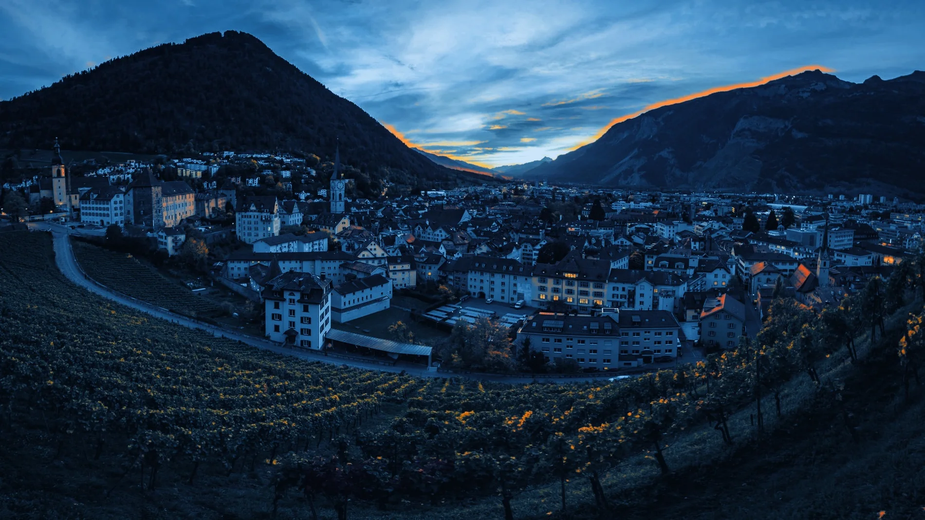 Blick über die Churer Altstadt zur blauen Stunde, mit den Bündner Alpen im Hintergrund