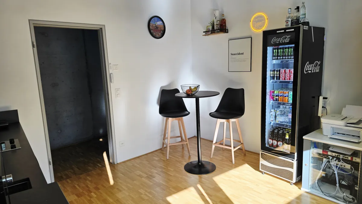 Bar-Ecke mit Stehtisch, Getränkekühlschrank und Neonschild