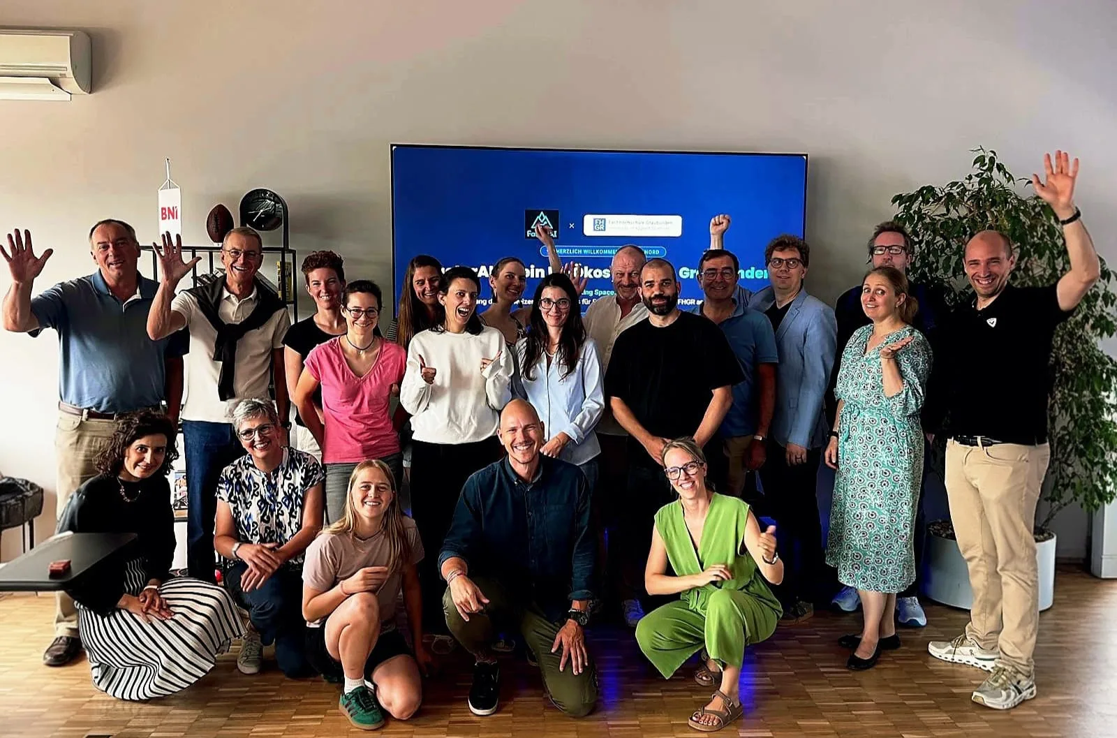 Gruppenfoto der FactorAI-Community mit der FH Graubünden vor dem grossen Screen