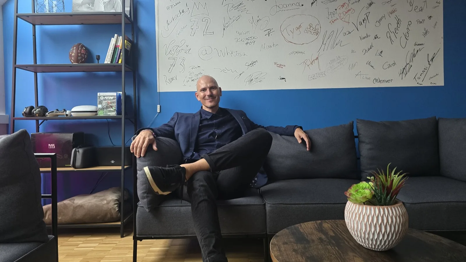 Sebastian Früh auf dem Sofa in der FactorAI Lounge vor der Signature Wall